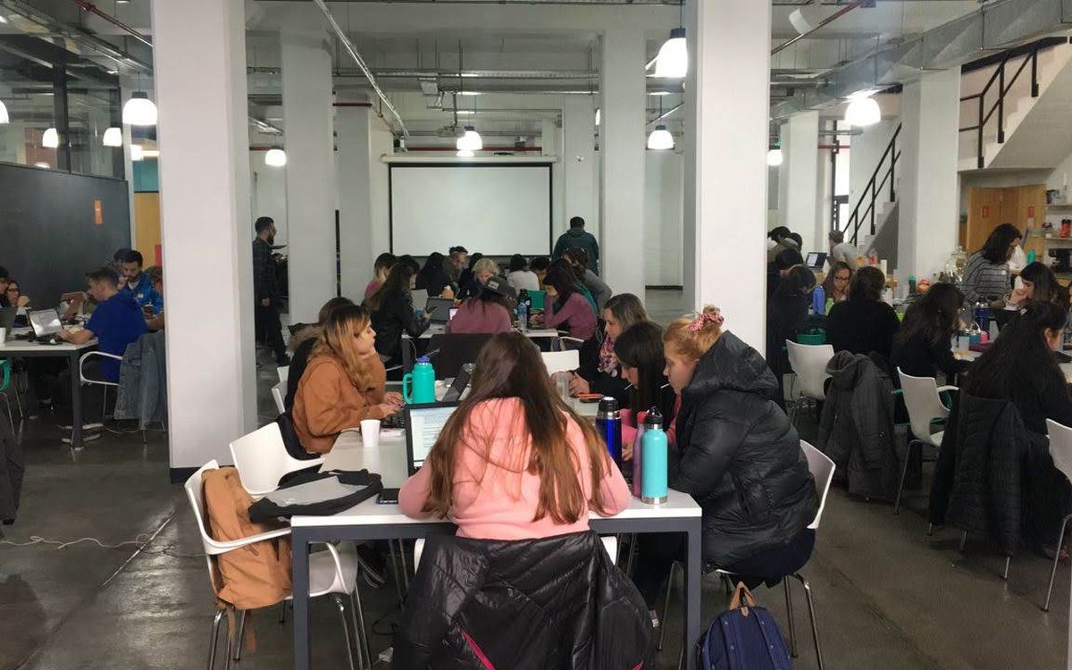 Sala llena de gente trabajando en mesas durante una jornada