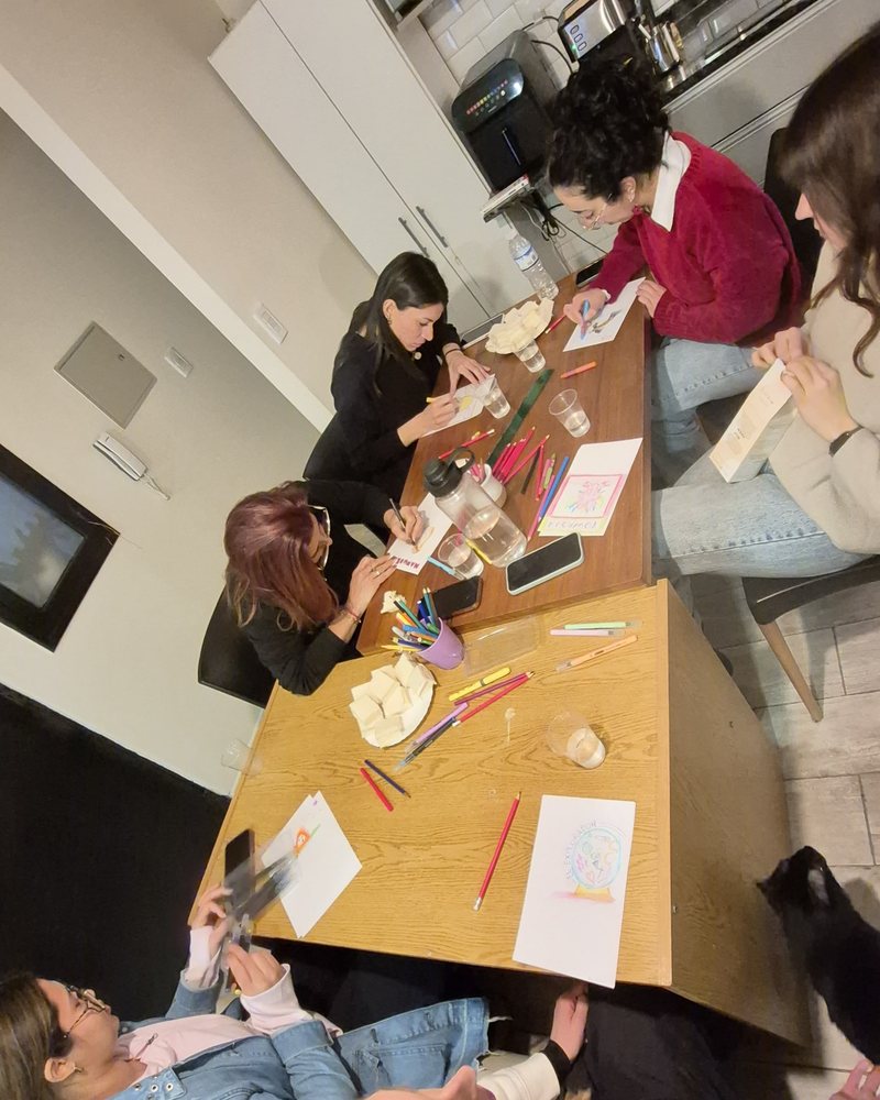 Grupo trabajando alrededor de una mesa con hojas, lápices y materiales